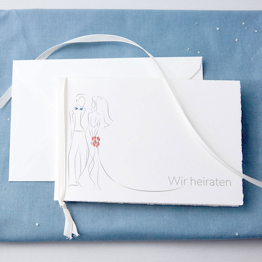 Vergrößerte Abbildung Geschlossene Karte mit Kuvert und Band vor blauem Tuch.