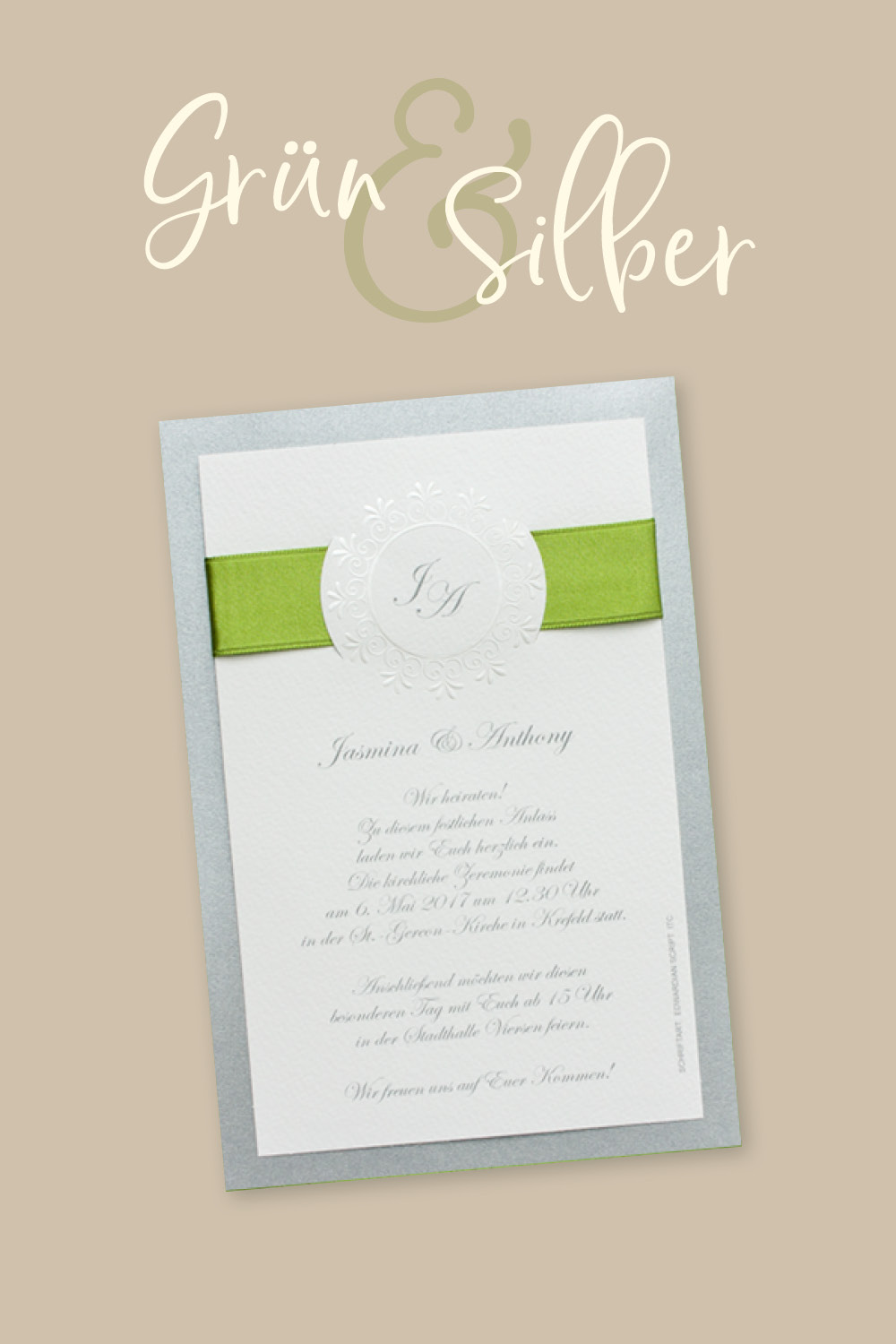 Weiße Hochzeitseinladungen, aufgeklebt auf silbernem, schillernden Trägerkarton, oben von einer grünen Schleife umfasst.